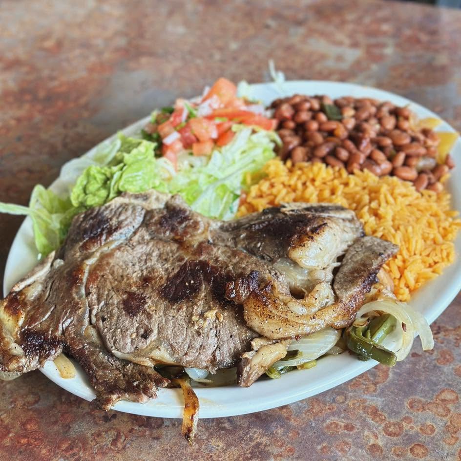 Grilled carne asada steak sliced and plated with sides.