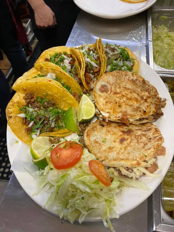 Large combo plate with tacos, rice, beans, and fresh garnishes.